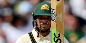 Usman Khawaja of Australia raises his bat after reaching a half-century on day five of the first Test.