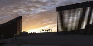 A pair of migrant families from Brazil passes through a gap in the border wall to reach the United States after crossing from Mexico in Yuma,Arizona. 