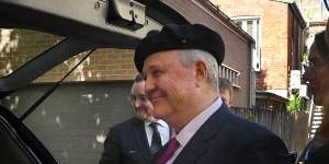 Tim Olsen (left) wears his father John Olsen’s beret before returning it on top of his coffin in Paddington on Thursday.