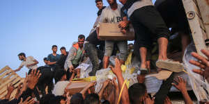 Palestinians distribute food aid that entered the southern Gaza Strip through the UN World Food Program in the Wadi Gaza area on Saturday.
