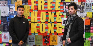 Two pro-democracy protesters stand in front of a"Lennon Wall"at the University of Technology Sydney.