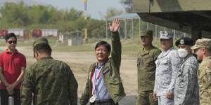 Philippine President Ferdinand Marcos jnr waves beside a US M142 high mobility artillery rocket system at the drills on Wednesday.
