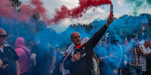 A man holds a flare during a protest outside The Bell Hotel in Epping in July.