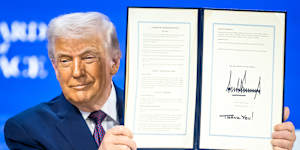 US President Donald Trump holds up a signed Board of Peace charter.