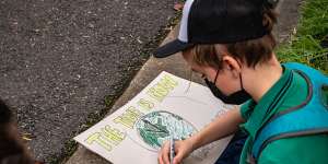 A student prepares a sign for the Friday protest. 