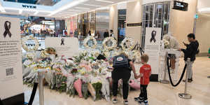 A mother and young son leave flowers at a memorial to the victims of last week’s Westfield Bondi Junction tragedy.