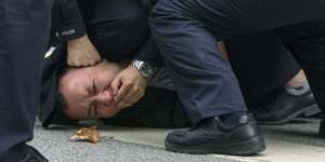 Police pin down a protester on a street in Shanghai on Sunday.