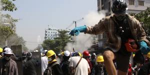 Protesters are dispersed as riot police fired tear gas behind a makeshift barricade in Yangon.