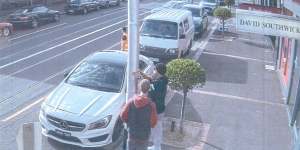 CCTV footage captures Jimeone Roberts and another man attaching a swastika sticker to a pole in Caulfield on May 12.