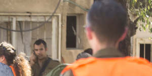 Security force personnel look at a burned car after a rocket fired from Gaza Strip hit on Saturday. 