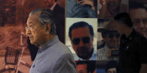 Malaysian Prime Minister Mahathir Mohamad walks by a board displaying his photos in Putrajaya,Malaysia.