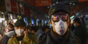 Chinese shoppers wear masks in Beijing. The rate of new coronavirus cases continues to decline in that country. 