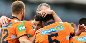 Together:Knights players embrace after a try against the Wests Tigers on Sunday.