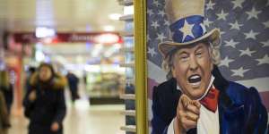 People walk past a caricature picture of US President Donald Trump on sale in a shopping mall in Moscow.