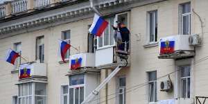 Workers hang Russian flags at an apartment building in Luhansk,Luhansk People’s Republic controlled by Russia-backed separatists,eastern Ukraine.