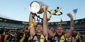 Trent Cotchin holds the premiership trophy aloft as the Tigers leave the field after winning the 2019 grand final.