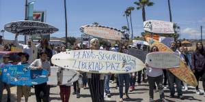 Locals in Ensenada,Mexico,march to protest the disappearance of foreign surfers. Surfboard signe,centre,reads:“Beaches - safety - freedom - peace”.