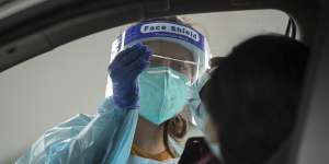 A health worker carries out a COVID-19 test at the Merrylands drive-through clinic in Sydney.