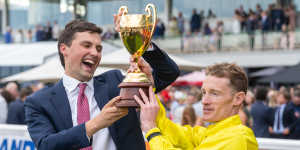 Co-trainer Sam Freedman and jockey Mark Zahra hold aloft the Caulfield Cup after Without A Fight’s win on Saturday.
