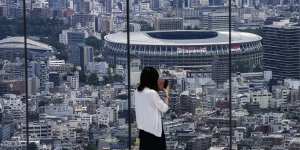 A person takes a picture from an observation deck of the National Stadium,where the Opening Ceremony will be held on July 23. 