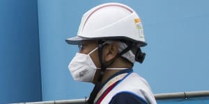 An employee walks past storage tanks for contaminated water at the tsunami-crippled Fukushima Dai-ichi nuclear power plant.