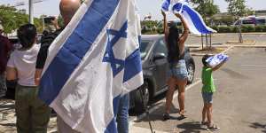 People wave Israeli flags as a helicopter carrying the rescued hostages lands in Israel on Saturday.
