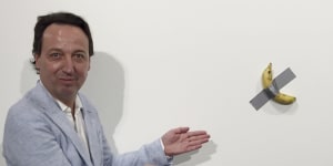 Gallery owner Emmanuel Perrotin poses next to Maurizio Cattlelan's'Comedian'at the Art Basel exhibition in Miami Beach,Florida. The work sold for $US120,000 – and was also eaten.