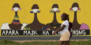 A woman walks past a coronavirus-themed mural promoting the use of face mask in public to protects against COVID-19 in Vereeniging,South Africa.