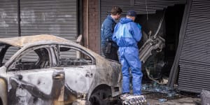 Detectives collect evidence from a scene in Hadfield where a car was rammed into a greengrocer and set on fire last year.