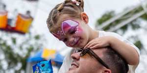 Lola,2,rests on her father Guy Power’s shoulders,happy with food and facepaint.