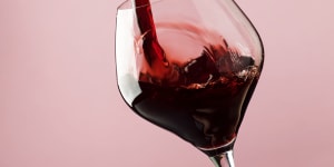 French dry red wine,pours into glass,trendy pink background,space for text,selective focus Red wine generic iStock