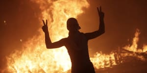 An anti-government protester makes victory signs in front a fire set by protesters to block a road during a demonstration in Beirut,Lebanon.