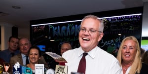Scott Morrison pulls a beer and meets the patrons at the Cazalys Palmerston Club near Darwin on Anzac Day.