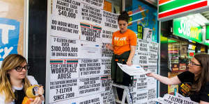 Protesters from the Young Workers'Centre pin signs to the windows of Melbourne 7-Eleven store highlighting the company's worker exploitation and wage fraud scandal. 