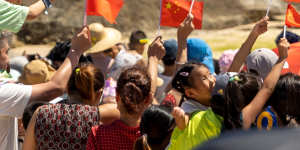 Tourists wave Chinese national flags on the Qishuiwan Beach in Wenchang.