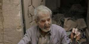 A man sits in front of his damaged house in Aleppo after surviving an apparent barrel bomb dropped by Syrian forces.