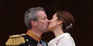 The new king and queen kiss on the palace balcony.