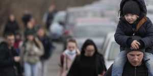 Ukrainian refugees walk alongside vehicles lining up to cross the border from Ukraine into Moldova on Saturday.