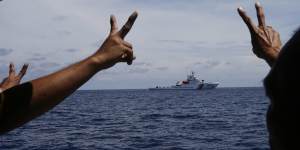 Philippine crewmen gesture towards a Chinese ship in the South China Sea