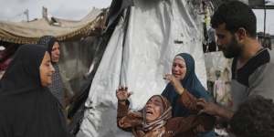 Displaced Palestinians inspect their tents destroyed by Israeli strikes at a UN facility west of Rafah.