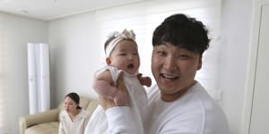 Lee Dong Kil holds his daughter Lee Yoon Seol with wife Ryu Da Gyeong on sofa. 
