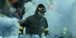 A firefighter removes flares from the pitch following Napoli’s 1-1 draw in Udine.