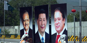 Workers walk past a billboard showing pictures of Chinese President Xi Jinping,centre,with Pakistani President Mamnoon Hussain,left,and Prime Minister Nawaz Sharif in Islamabad,Pakistan.