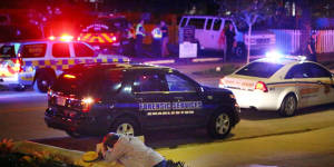 A man kneels across the street from where police gather outside the Emanuel AME Church following a shooting Wednesday.