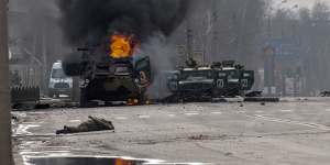 A Russian armoured personnel carrier burns in Kharkiv - with what appears to be a body in the foreground.