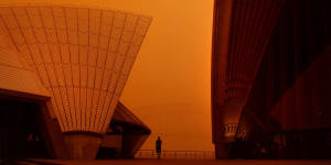 A man is dwarfed by the sails of the Opera House as a blanket of red dust covers the city in 2018.