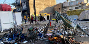 People inspect burned tents outside the heavily fortified Green Zone in Baghdad,Iraq,on Saturday,after at least one protester was killed and scores of people,mostly members of Iraqi security forces,were injured during protests. 