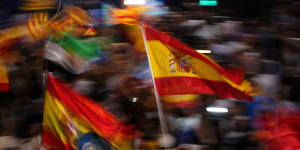 Supporters of Spain’s mainstream conservative Popular Party supporters wave flags.
