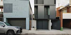 The house (right) has a two-level black steel facade that adds a sense of mystery.