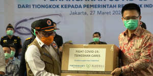 Chinese and Indonesian officials pose with aid supplied by China as it arrives in Jakarta.